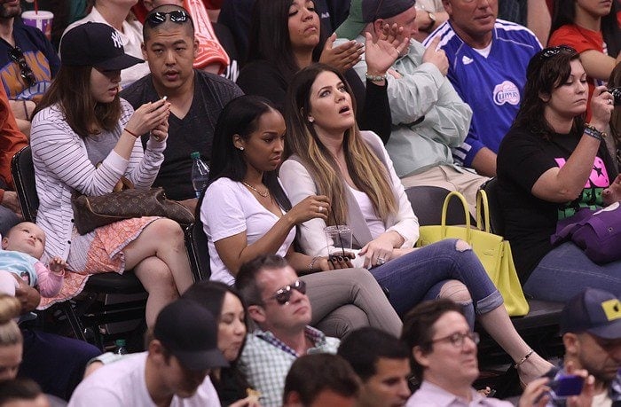 Khloe Kardashian wears a long-sleeved tee, jeans and a vest to an NBA game