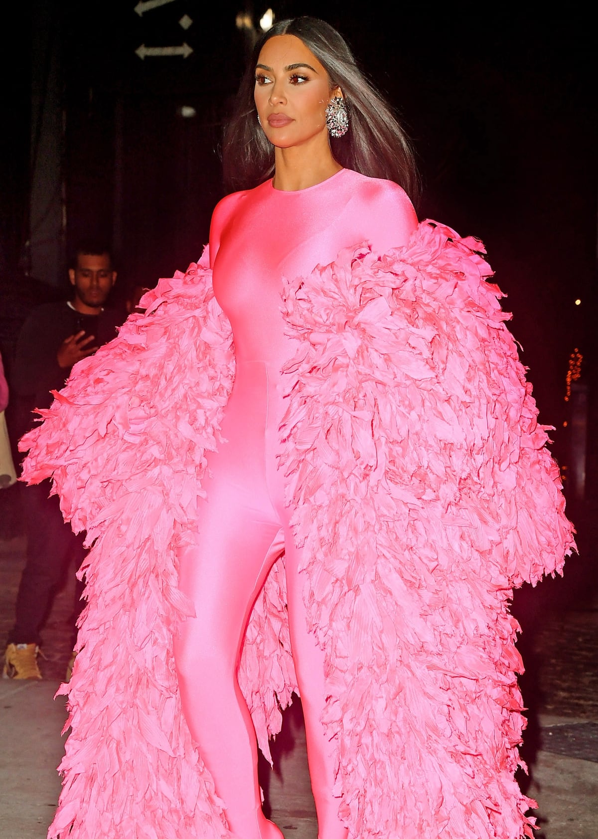 Kim Kardashian styled a hot pink catsuit by Balenciaga with a luxurious ruffled coat