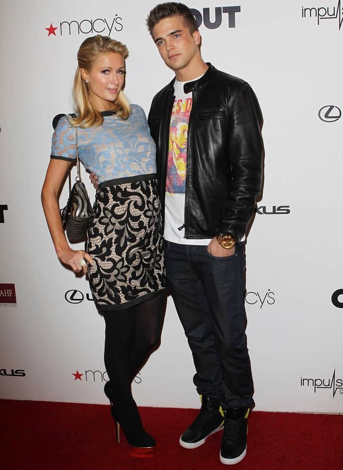 Paris Hilton stuns in a lace mini dress paired with black stockings and platform heels, while posing on the red carpet with her then-boyfriend, River Viiperi