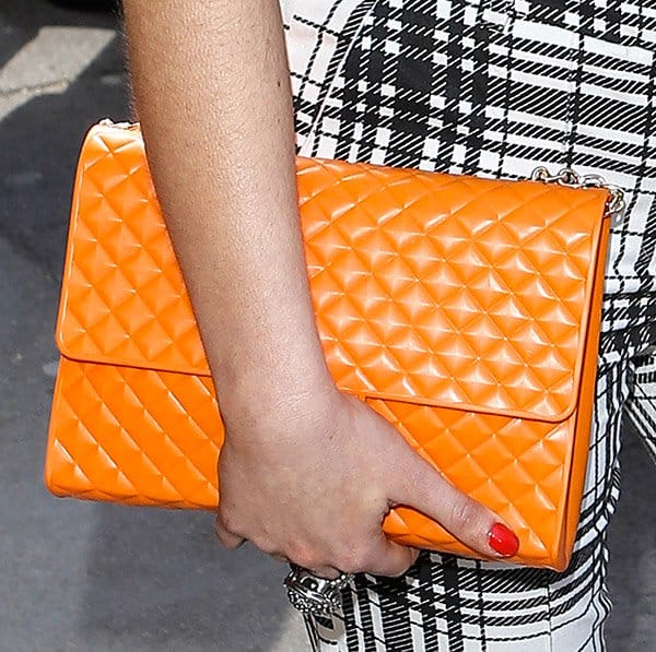 Rachel Shenton elevates her TRIC Awards ensemble with a striking orange quilted clutch