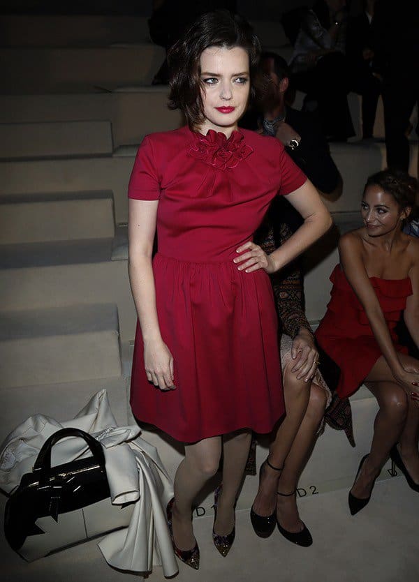Roxane Mesquida wears a red ruched dress to the Valentino fashion show held during Paris Fashion Week