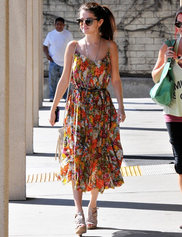 Selena Gomez leaves a nail salon, showcasing her boho-chic style with a floral dress and glam accessories