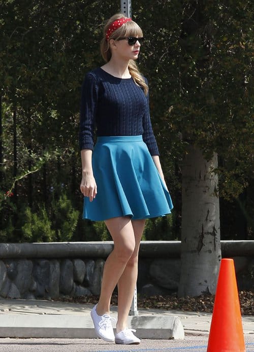 Taylor Swift flaunts her legs in a cable knit top and a light blue circle flared skirt on the set of a photoshoot in Los Angeles