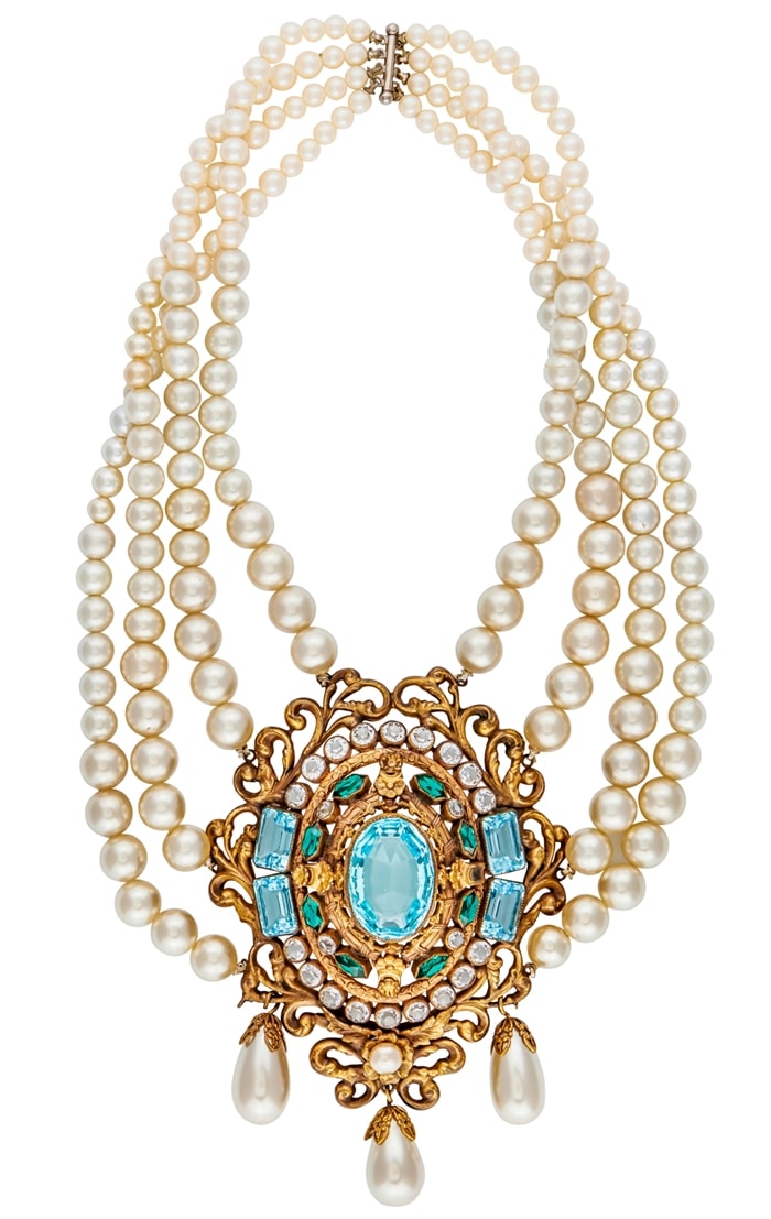A graduated, four-strand simulated pearl necklace centering on a gold plated filigree medallion set with simulated aquamarine, emeralds, and diamonds with pearl drops. It was worn by Bette Davis in "The Virgin Queen," a 1955 DeLuxe Color historical drama film directed by Henry Koster