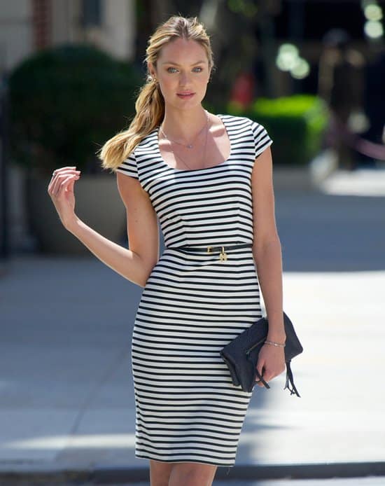 The striped figure-hugging dress styled with a slim belt, a large black clutch, and a pair of low-heeled pumps
