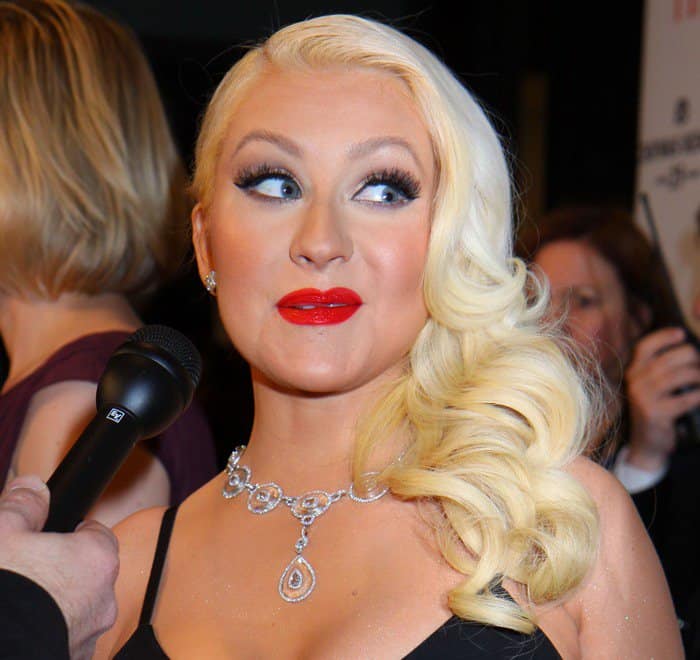 Christina Aguilera strikes a pose with her signature bold red lips and glamorous curls, epitomizing timeless beauty