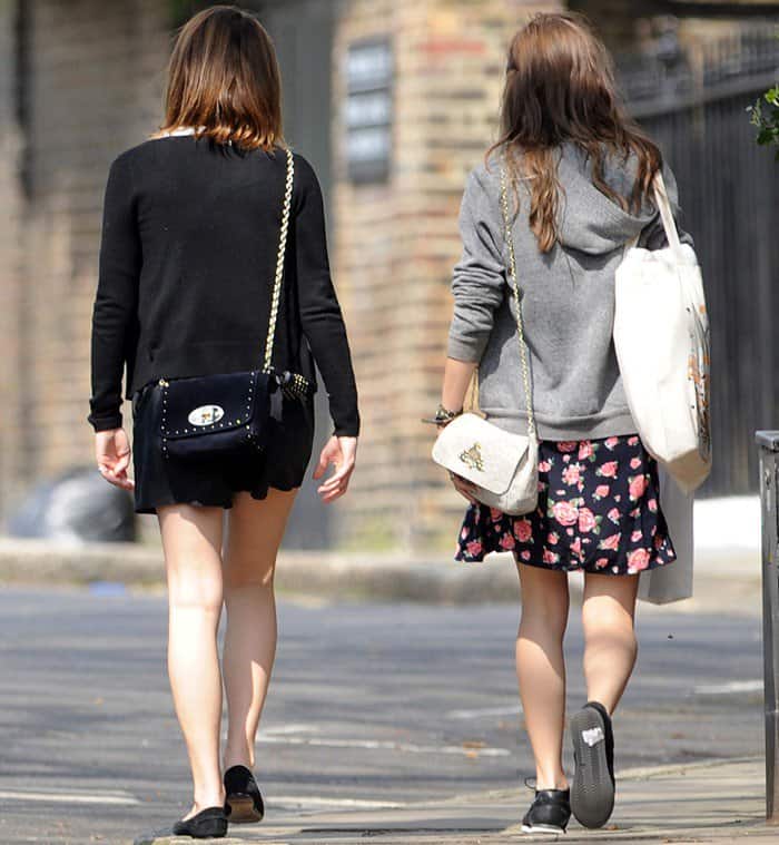 Emma Watson enjoys a sunny spring day in West London, showcasing her style in chic black shorts during a leisurely stroll with a friend, April 25, 2013