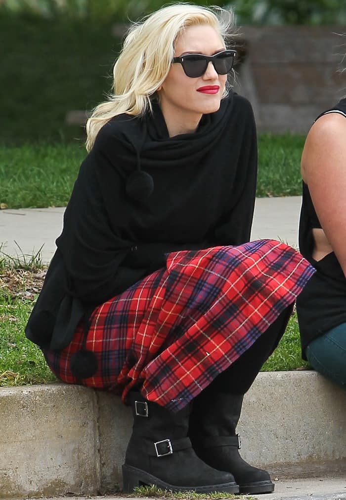 Gwen Stefani wears Oliver Peoples Sofee sunglasses with a long red tartan skirt and Dr. Martens Diza Ankle biker boots