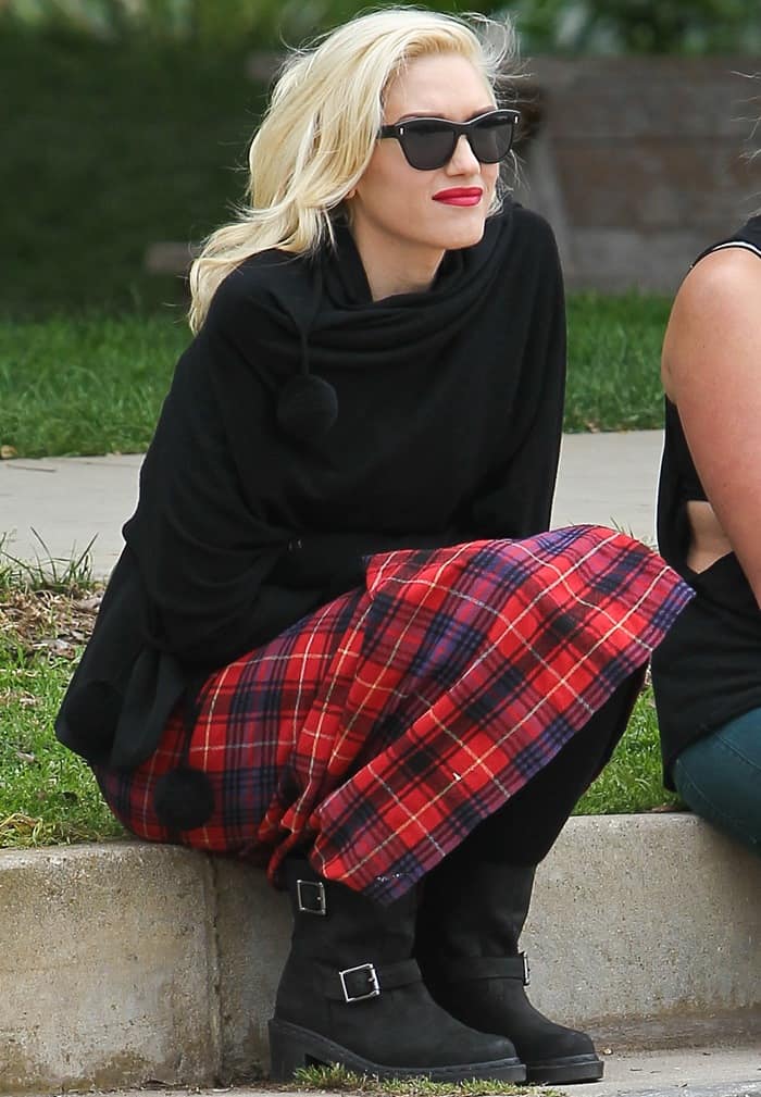Gwen Stefani wears Oliver Peoples Sofee sunglasses with a long red tartan skirt and black Dr. Martens Diza ankle biker boots featuring double buckle straps and a rugged sole