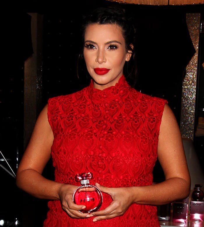 Kim Kardashian holds a bottle of her Glam by Kim Kardashian floral fruity fragrance for women