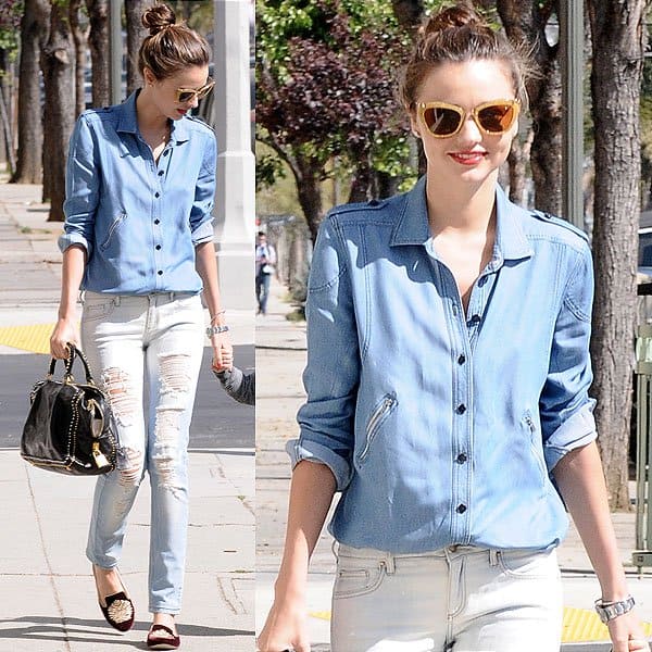 Miranda Kerr sported a casual-chic ensemble with a denim shirt, ripped jeans, statement sunglasses, a studded designer tote, velvet smoking slippers, and a classic Rolex watch