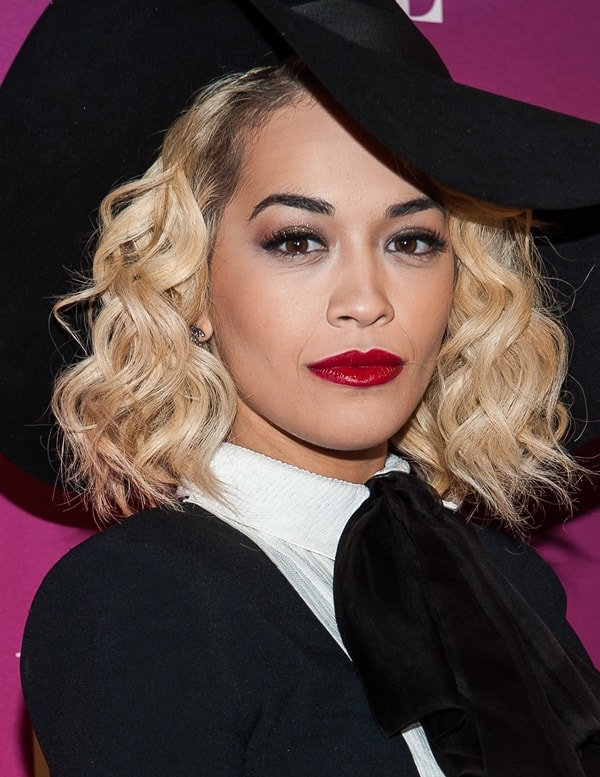 Rita Ora's outfit featured a sophisticated black tuxedo-style dress with a unique rise-and-fall hemline, adorned with a striking white sequin-embellished collar, bib, and cuffs