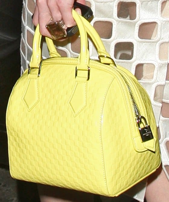 Close-up of Erin O'Connor's chic Louis Vuitton Speedy Cube PM in vibrant yellow Damier facette, captured at a London soirée