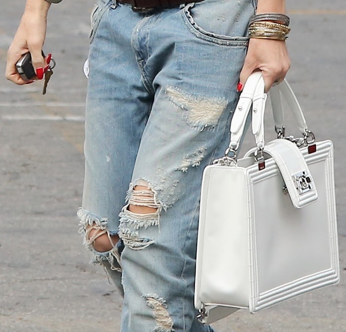 Gwen Stefani keeping her accessories simple — a geometric white purse and a stack of bangles