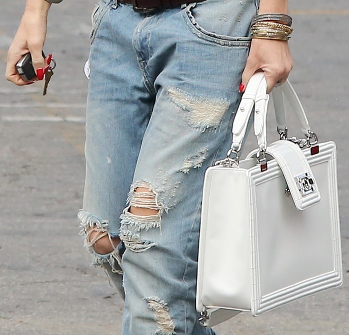 Simplicity meets style: Gwen Stefani accessorizes with a geometric white Chanel purse and bronze bangles