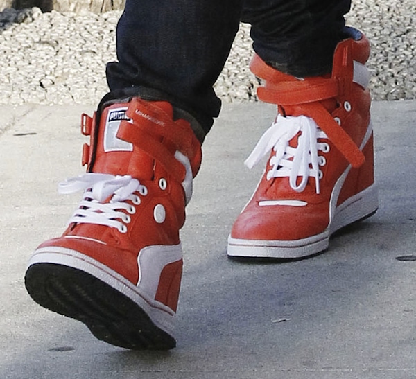 Gwen Stefani's orange wedge sneakers from Puma add color to her ensemble