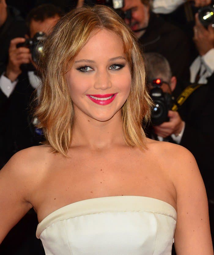 Jennifer Lawrence's look was completed with a tousled center-parted hairstyle, Chopard jewelry, and a striking fuchsia pink lipstick