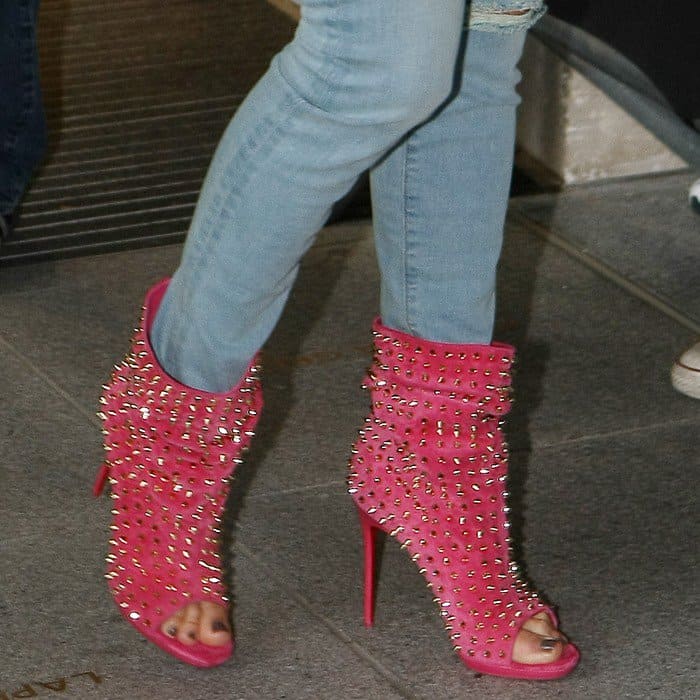 Jennifer Lopez accents her conservative radio interview outfit with bold Christian Louboutin 'Guerilla' boots in red suede