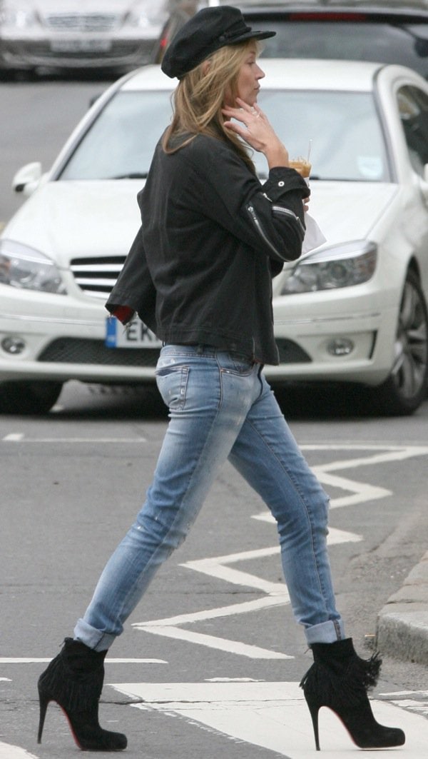 Kate Moss in cuffed and faded jeans, a black zipper-detailed jacket, and a black newsboy cap