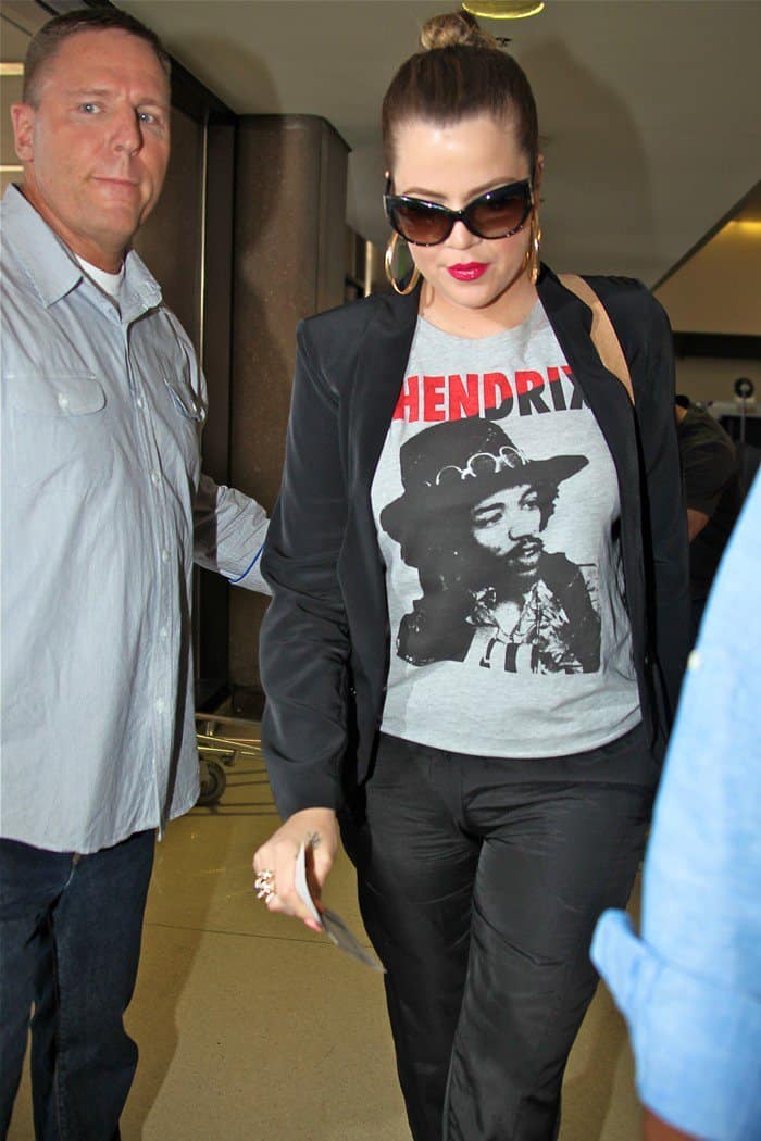 Khloe Kardashian pairs a Forever 21 'Hendrix' muscle tee with Tom Ford cat-eye sunglasses, showcasing a vintage-chic look at LAX