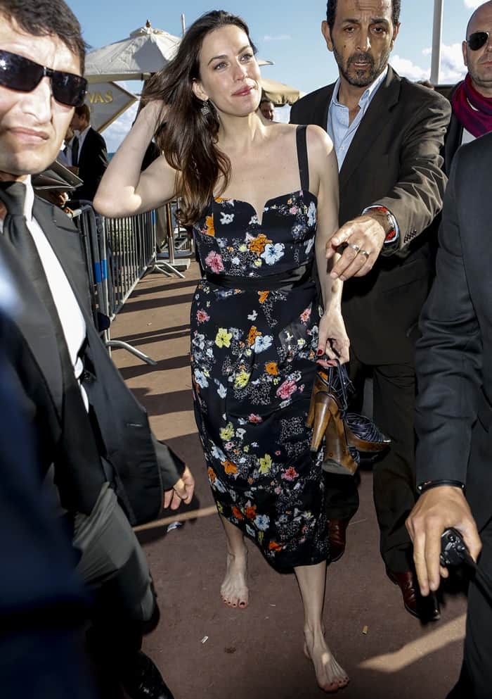 Liv Tyler embraces the carefree spirit of Cannes, going barefoot in her elegant floral dress by the seaside