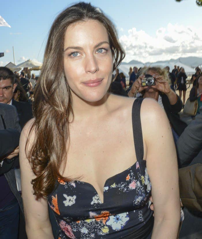 Liv Tyler's blue eyes shine against the backdrop of the Cannes Film Festival, complementing her floral Tanya Taylor dress