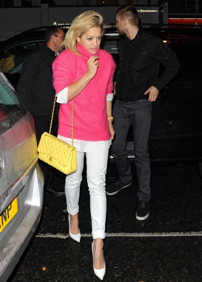 Rita Ora in a vibrant ensemble featuring a pink sweater, white jeans, and a yellow Chanel bag, spotted at the Electric Cinema with Calvin Harris on May 13, 2013