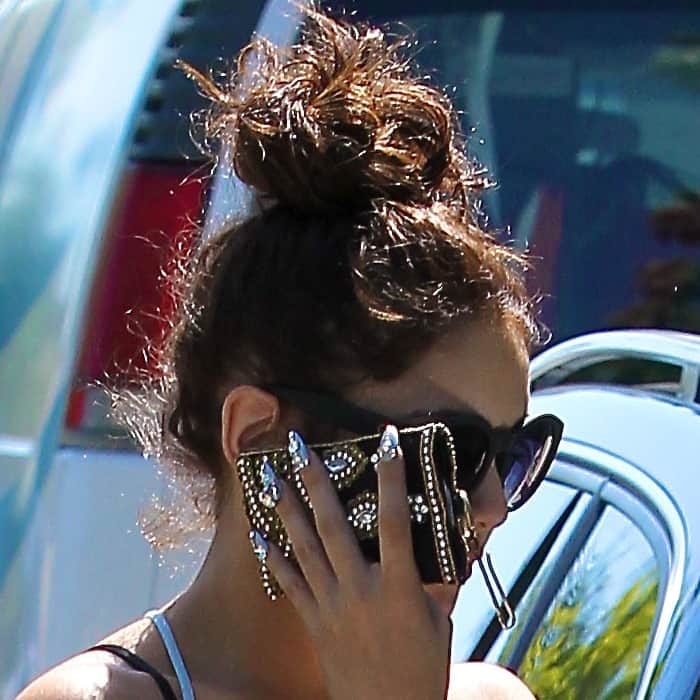 Vanessa Hudgens shields her face from the paparazzi while showing off her bold, bedazzled phone case and statement manicure