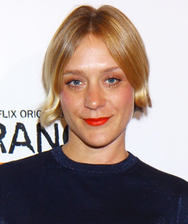 Chloë Sevigny radiates charm at the 'Orange Is the New Black' premiere, pairing her shimmering navy top with a bold red lip for a captivating, chic look