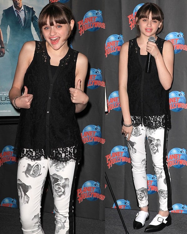 Joey King wearing a laced top, a pair of floral-printed jeans, and black-and-white shoes