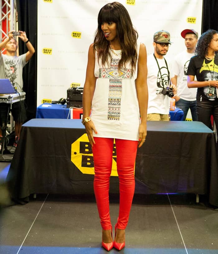 Full view of Kelly Rowland wearing her stylish ensemble, complete with red leather pants, red pumps, and gold chain jewelry during her album promotion event in New York City on June 18, 2013