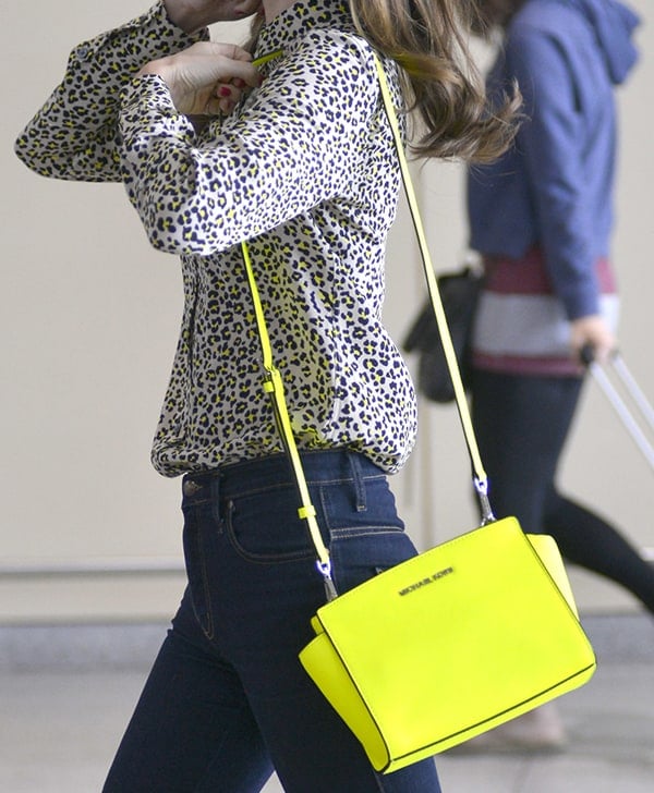 Fashion icon Miranda Kerr carries a neon yellow Michael Kors 'Selma' messenger bag, demonstrating her flair for integrating bold accessories with classic pieces