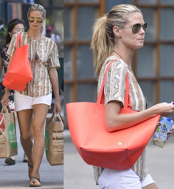 Heidi Klum brightens up her laid-back look in Manhattan with a bold orange tote, pairing it effortlessly with snakeskin print, white shorts, and thong sandals