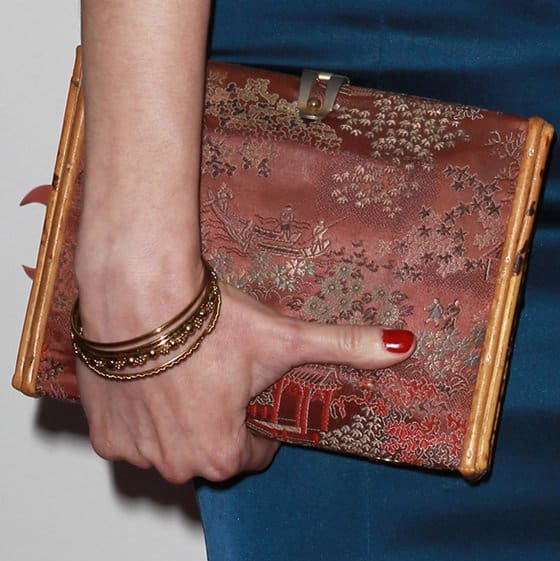 Mariana Klaveno toted an exquisite oriental-inspired satin clutch in shades of red and gold, gracefully complemented by golden bangles and bold red nail polish