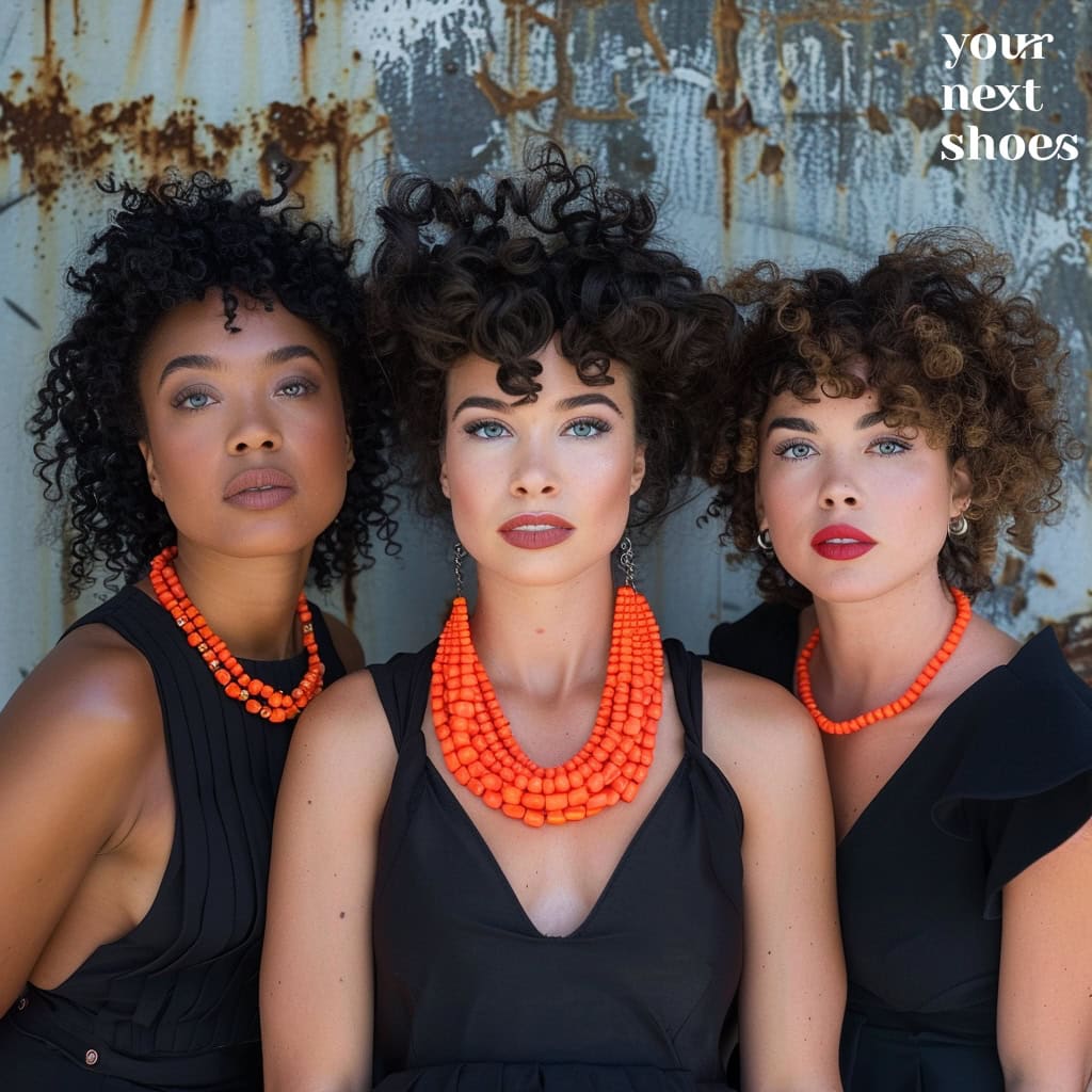 Three women with striking curly hairstyles exude confidence in black dresses complemented by bold orange necklaces