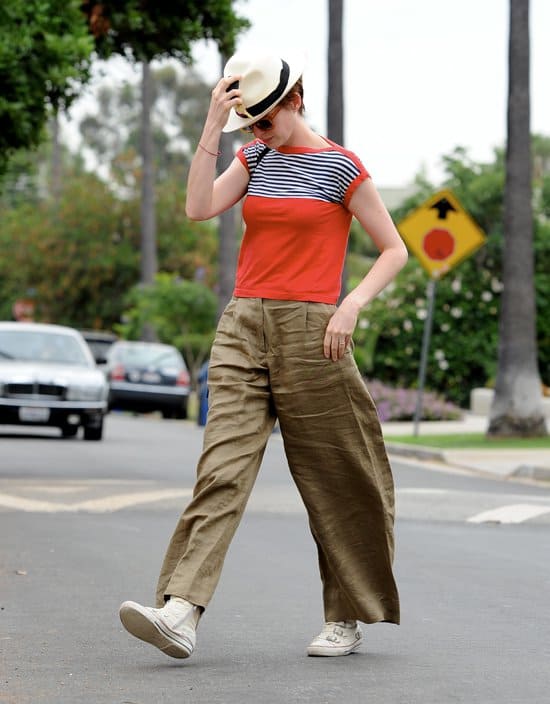 Anne Hathaway wearing big baggy trousers and a fedora hat while walking to a friend's house in California