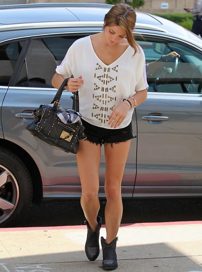 Ashley Greene arrives at Millennium Studios in West Hollywood on July 26, 2013, effortlessly blending edgy and boho-chic style with a Louis Vuitton 'Rivets' handbag, distressed black denim shorts, and studded Western-style ankle boots