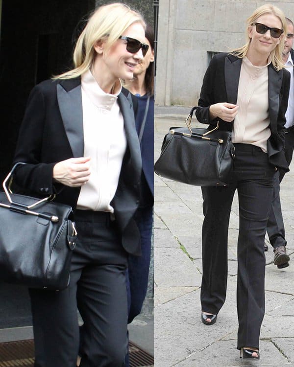 Cate Blanchett showcased her flair for power dressing in Milan, Italy, opting for a masculine-inspired black two-piece suit with a high-necked cream blouse, complemented by leather details on the blazer lapels, wide-leg trousers, dark shades, an oversized Viktor & Rolf black leather handbag, and patent peep-toe heels