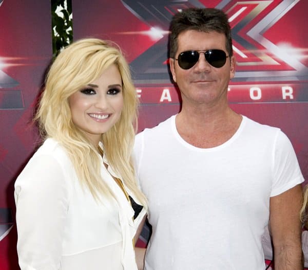 Demi Lovato and Simon Cowell pose together at an 'X Factor' event, showcasing a blend of talent and mentorship in the music industry