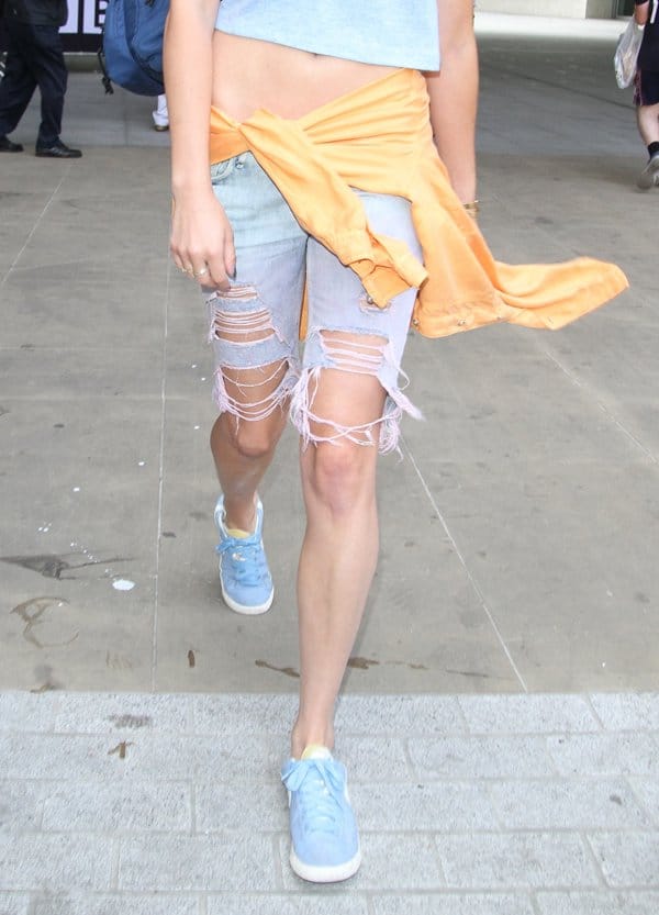 Eliza Doolittle turns heads with her unique fashion statement, featuring exceptionally distressed denim shorts paired with cool blue sneakers, as she confidently strides away from Radio 1 in London