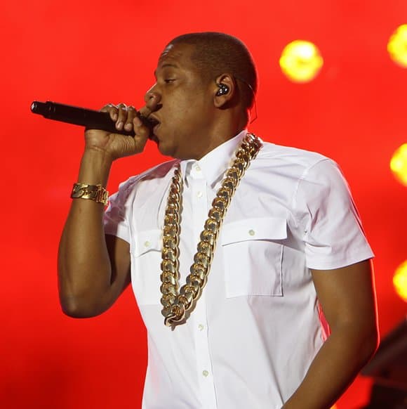 Jay-Z wears a white Theory “Feynold S. Wealth” shirt with a massive gold chain necklace