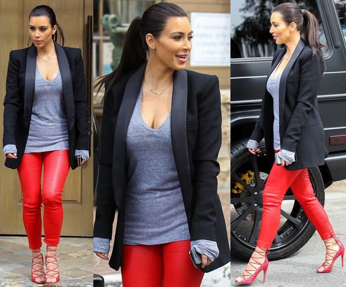 Kim Kardashian looks effortlessly chic in a sleek black blazer over a casual grey top paired with bold red leather pants and matching strappy heels, creating a stylish and modern outfit