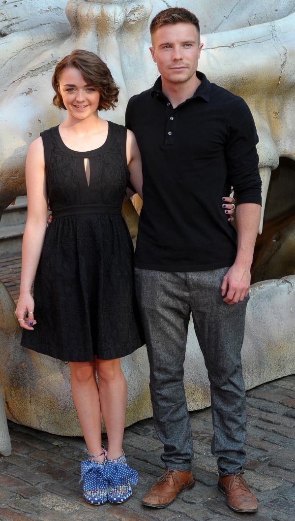 A huge dragon skull hulks behind Maisie Williams and co-star Joe Dempsie