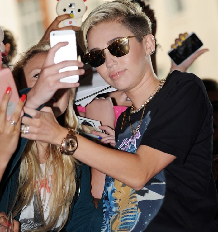 Miley Cyrus poses for photographs with fans outside the BBC Radio 1 studios in London, England, on July 18, 2013