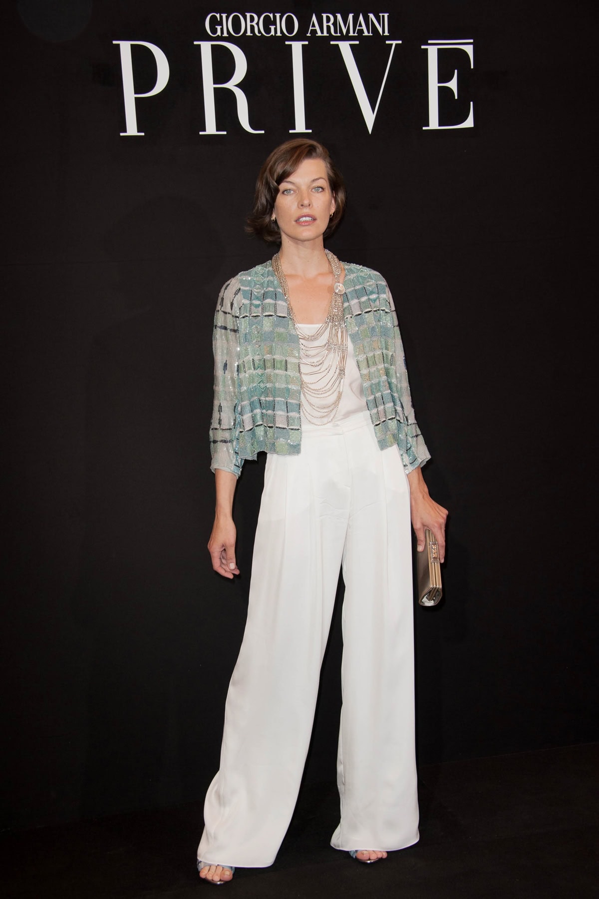 Milla Jovovich dazzled at the Giorgio Armani Couture Fall-Winter 2013-2014 in flared trousers, paired with a sea-green patterned jacket and strappy high heels, accessorized with a multi-strand beaded necklace and a small clutch