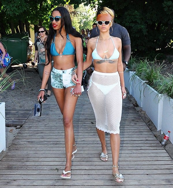 Joined by her best friend, Melissa Forde, Rihanna styled a white crochet midi skirt with a Mikoh Mundaka top, Miu Miu sandals, Mikoh Swimwear Venice bottoms, a tan Fleet Ilya visor, and Opening Ceremony sunglasses