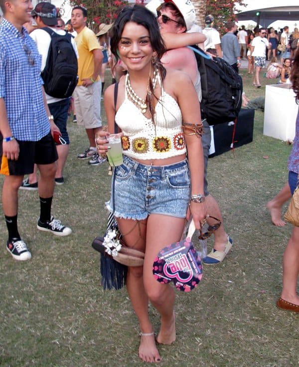 At Coachella in 2011, Vanessa Hudgens wore an eclectic ensemble featuring Wildfox high-waist shorts, a Litter SF chain leg garter, a Jj Winters mini fringe bag, multiple accessories including a Natalie B. Noga tribe necklace, Illesteva Leonard II sunglasses, Kettle Black sandals and bracelets, a Soixante Neuf snake arm cuff, a Chan Luu wrap bracelet, and Love Child feather earrings