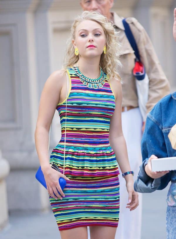 AnnaSophia Robb flaunts a big blonde 80s hairstyle and vibrant yellow earrings on the set of The Carrie Diaries