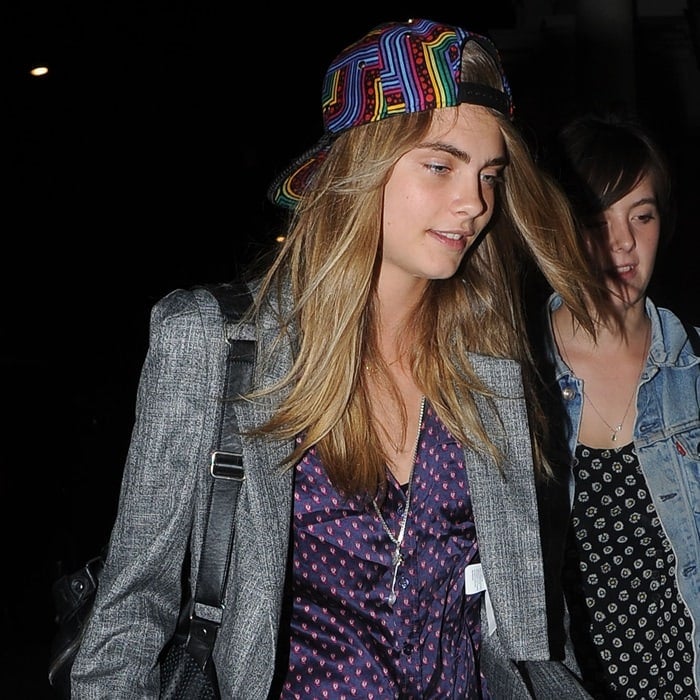 Model Cara Delevingne spotted in London on August 16, 2013, rocking a colorful cap, a grey suit, and a chic silk blouse after a night out with her sister Poppy Delevingne and Sienna Miller