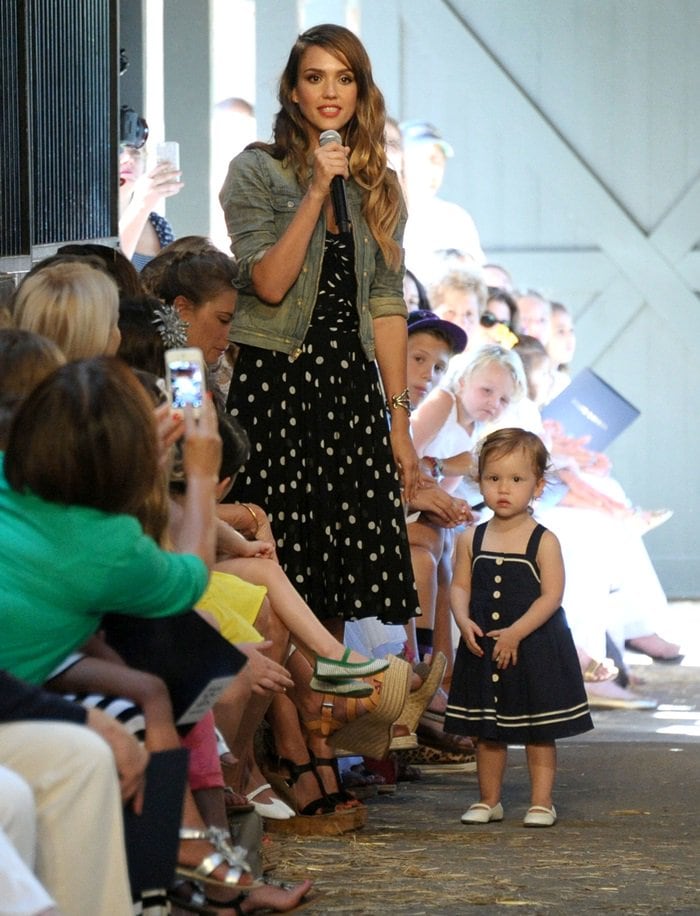Jessica Alba attended the Ralph Lauren Girls Fall Fashion Show on August 5, 2013, wearing a Ralph Lauren ensemble consisting of a turquoise denim Roper jacket, Fimesa calfskin wedges, and accessorizing with a Ricky bag